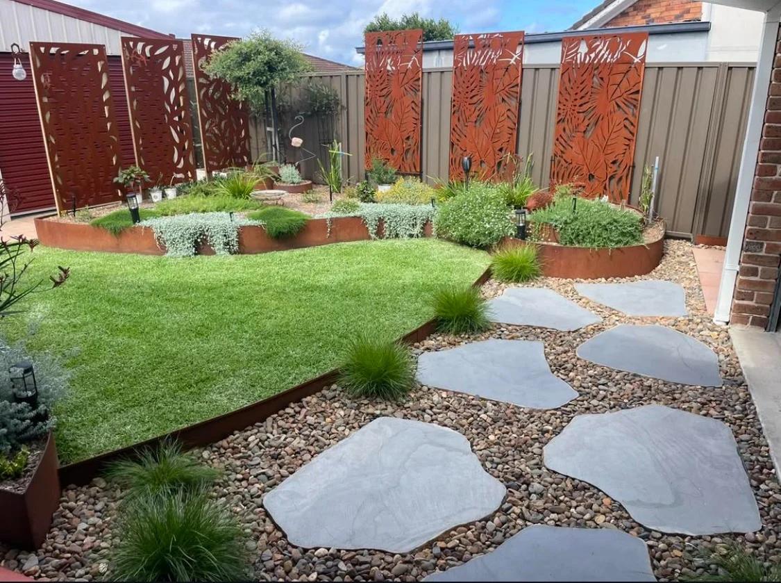 Detailed steel screens, curved garden beds, stone paths and planting in a completed courtyard